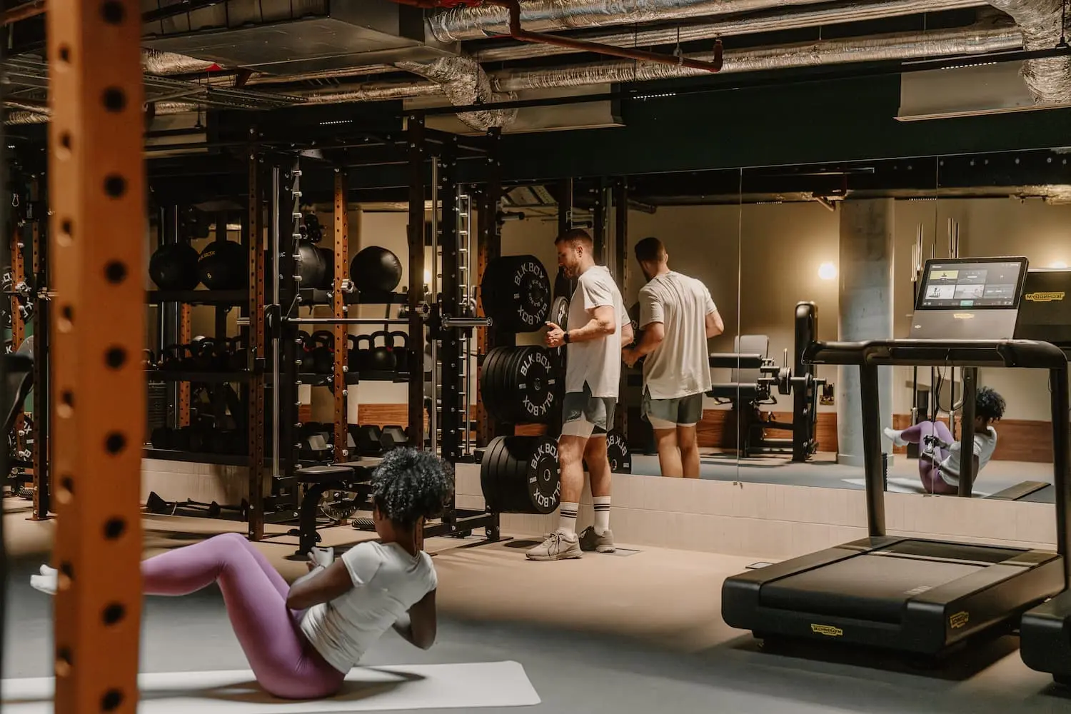 People training in a modern gym with weights and treadmills